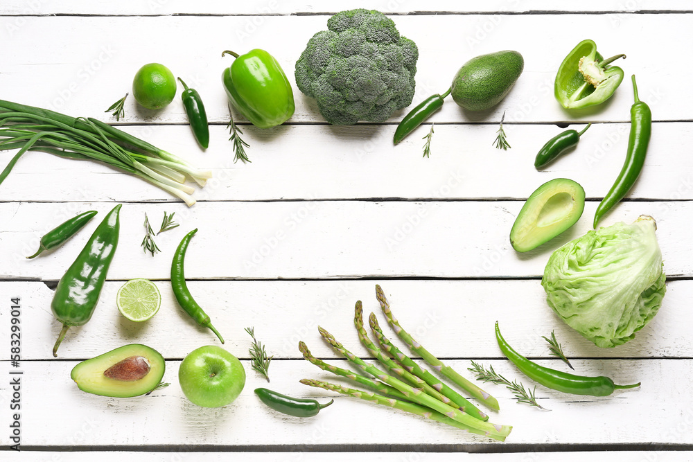 Frame made of different green vegetables on white wooden background