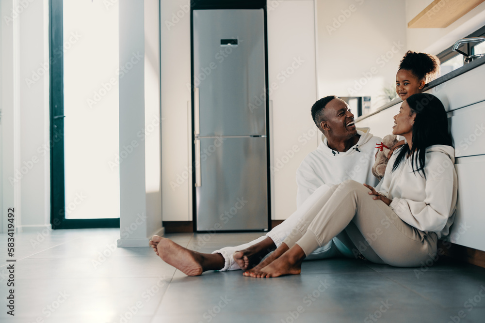 Mom and dad sitting on the kitchen floor with their daughter