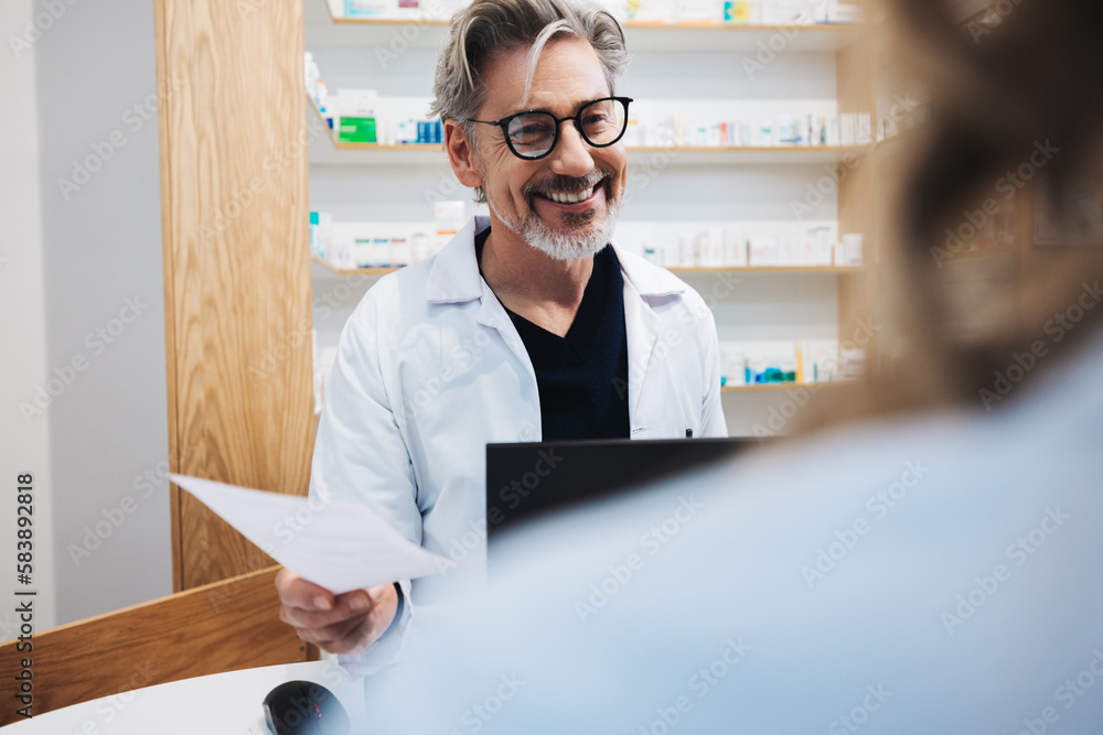 Senior pharmacist assisting a patient over the counter in a chemist