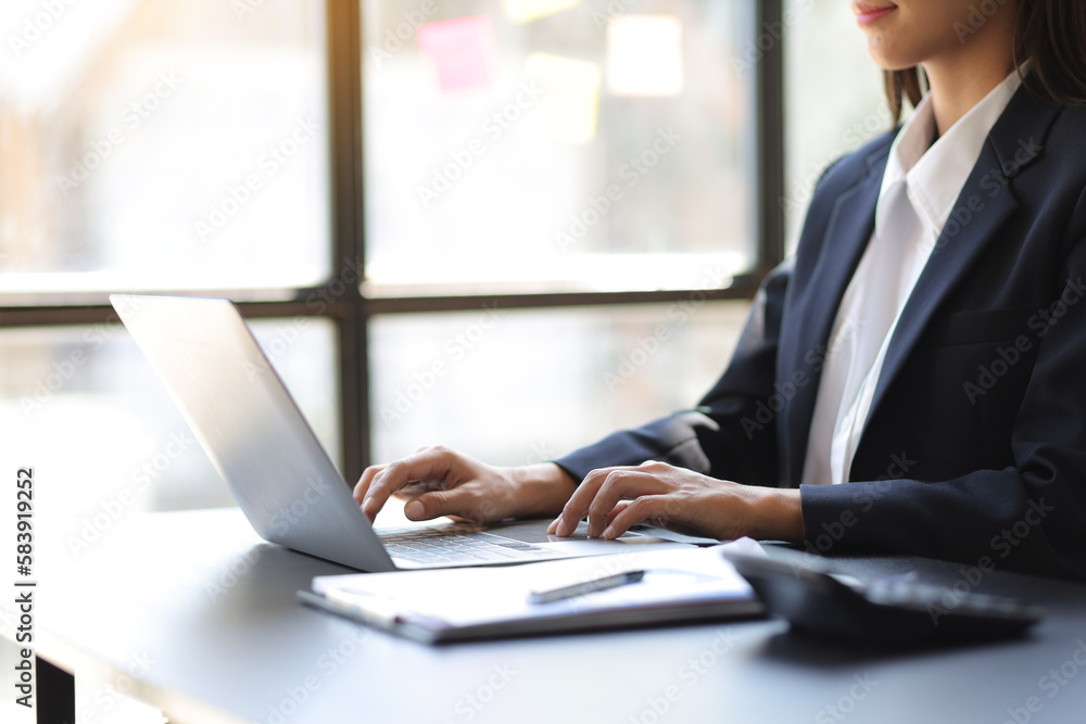 Businesswoman working with financial documents on laptop on office desk.