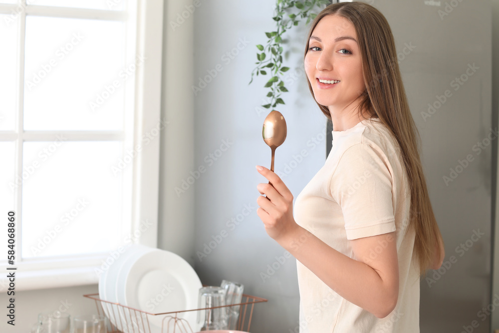 Beautiful woman with golden spoon in kitchen