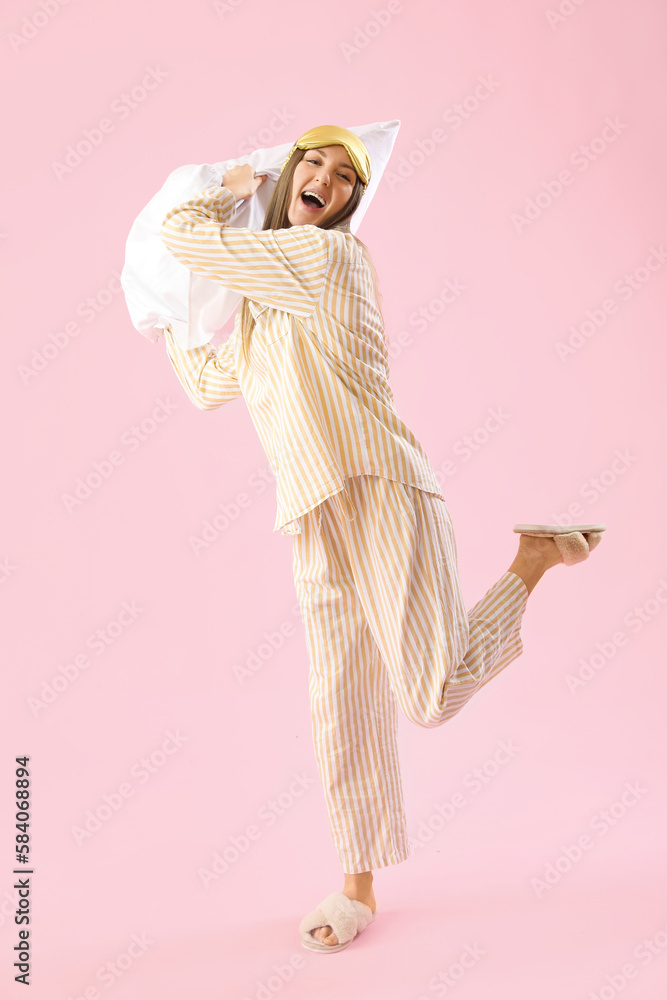 Young woman with sleeping mask and soft pillow on pink background