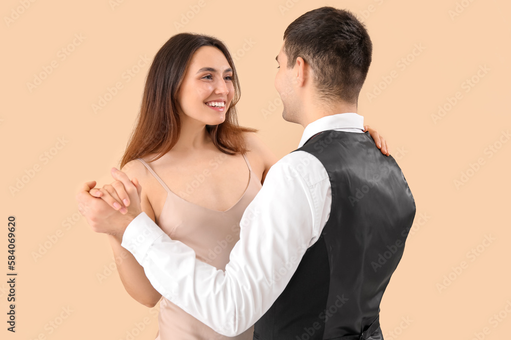 Elegant young couple dancing on beige background