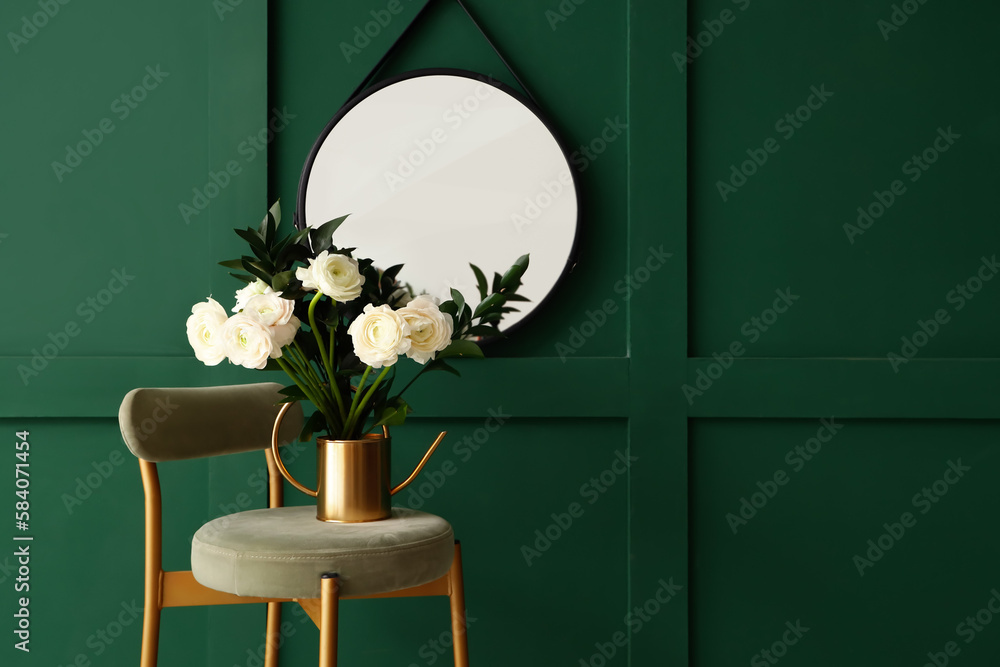 Vase with ranunculus flowers on stool near green wall in room