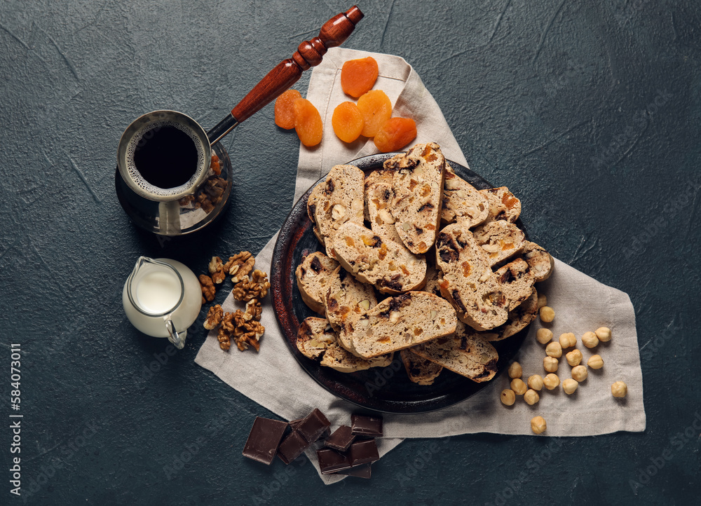 Composition with biscotti cookies, nuts, dried apricots, chocolate and coffee in cezve on black back