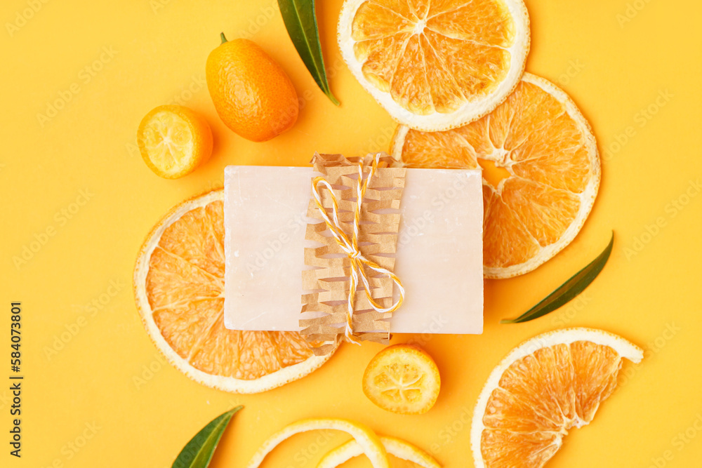 Composition with natural soap bar, dried orange slices and kumquat on yellow background, closeup