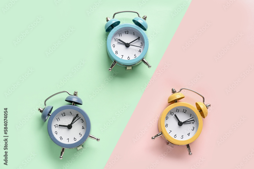 Three alarm clocks on color background