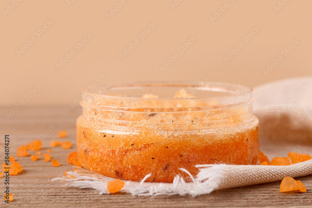 Jar of body scrub and sea salt on wooden background