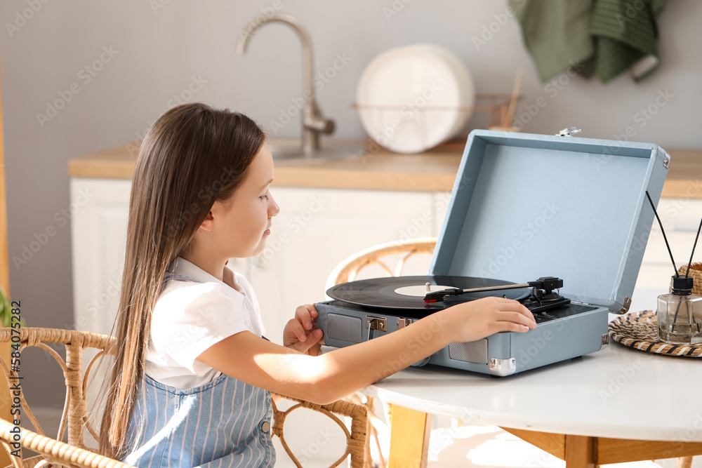 Little girl with record player at table in kitchen