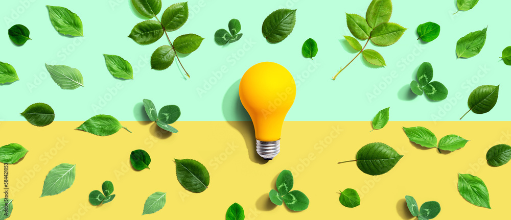 Yellow light bulb with green leaves - Flat lay