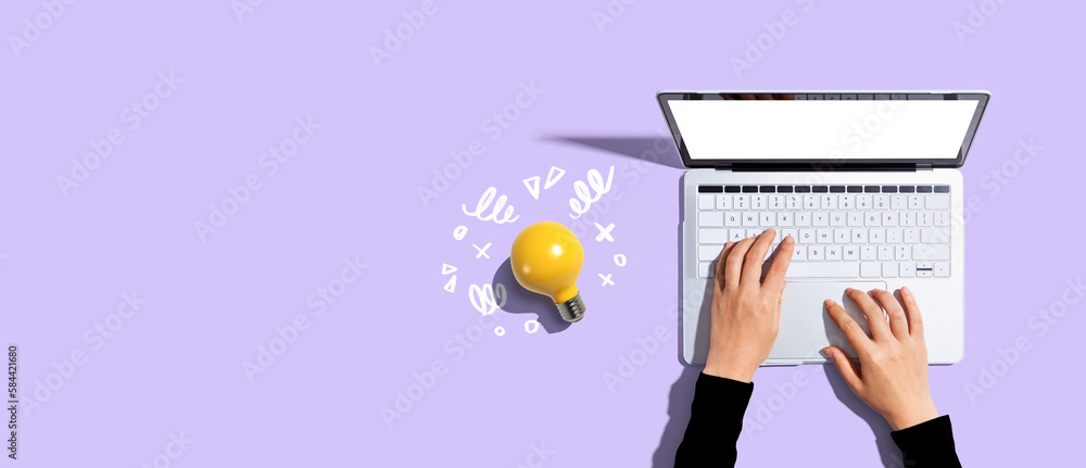 Person using a laptop computer and a light bulb - Flat lay