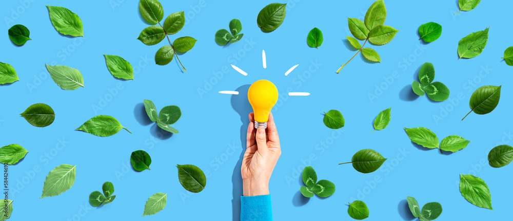 Person holding a light bulb with green leaves