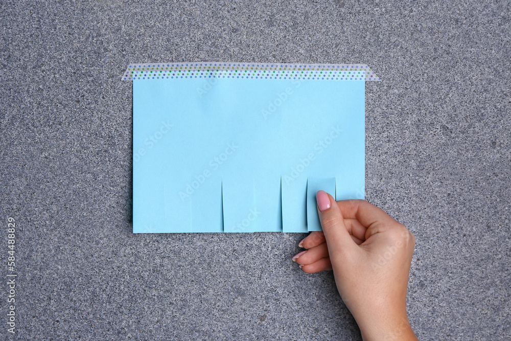 Woman tearing off paper ad from granite wall