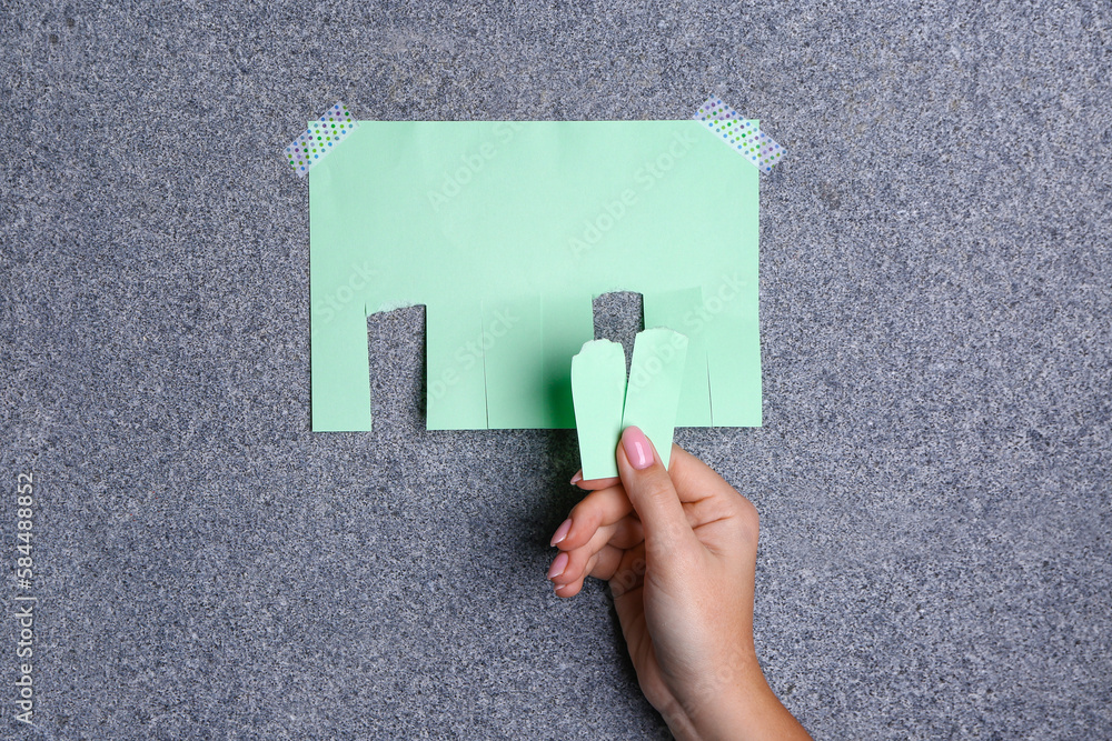 Woman tearing off paper ad from granite wall