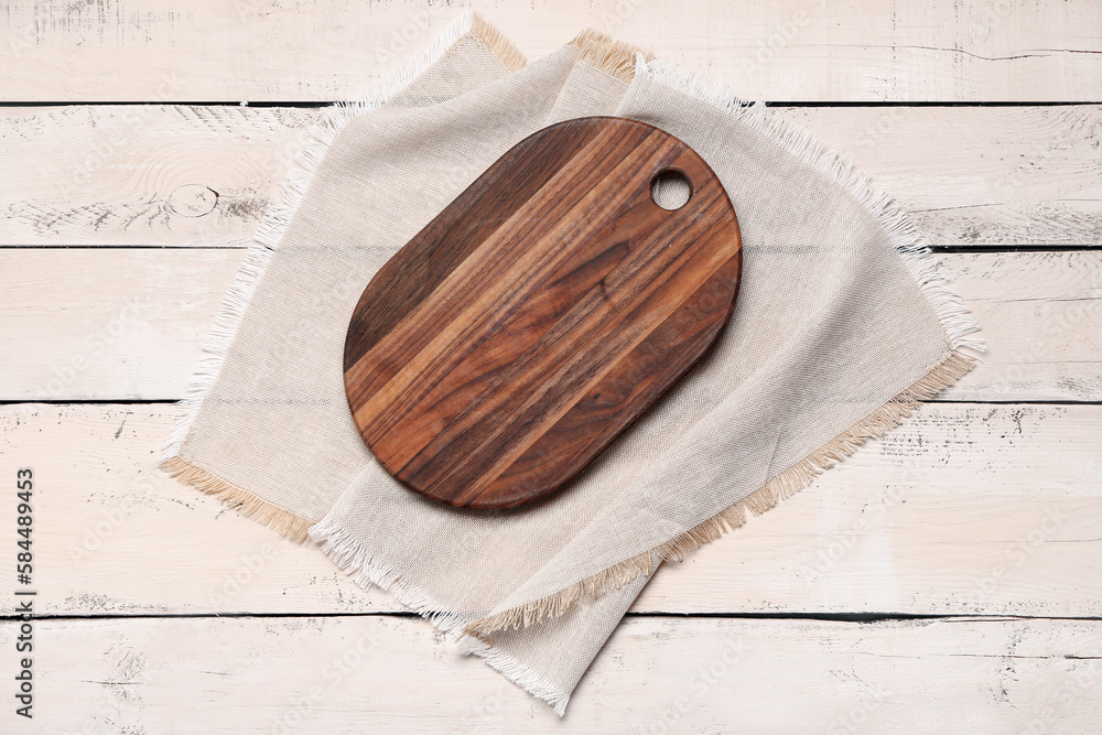 Cutting board with napkin on light wooden background