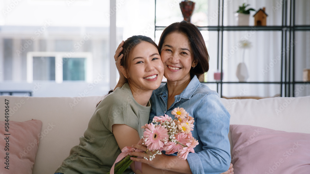 Happy time Mother day grown up child girl looking at camera cuddle hug give flower bouquet gift to m