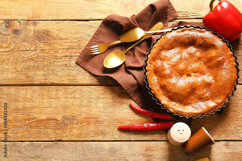 Composition with delicious meat pie in baking form and peppers on wooden table