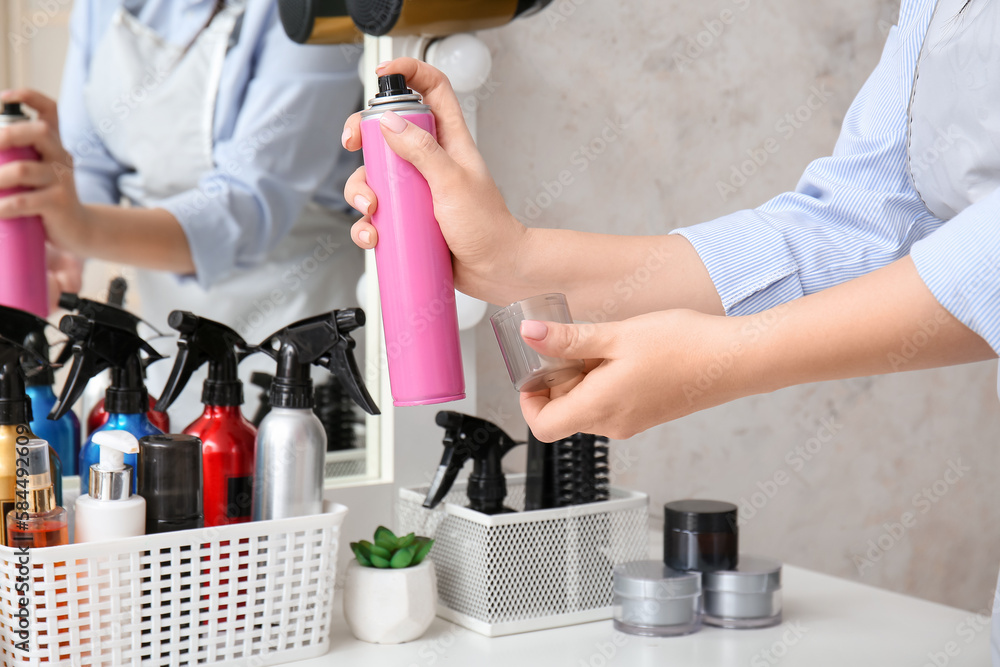 Hairdresser with spray at table in beauty salon, closeup