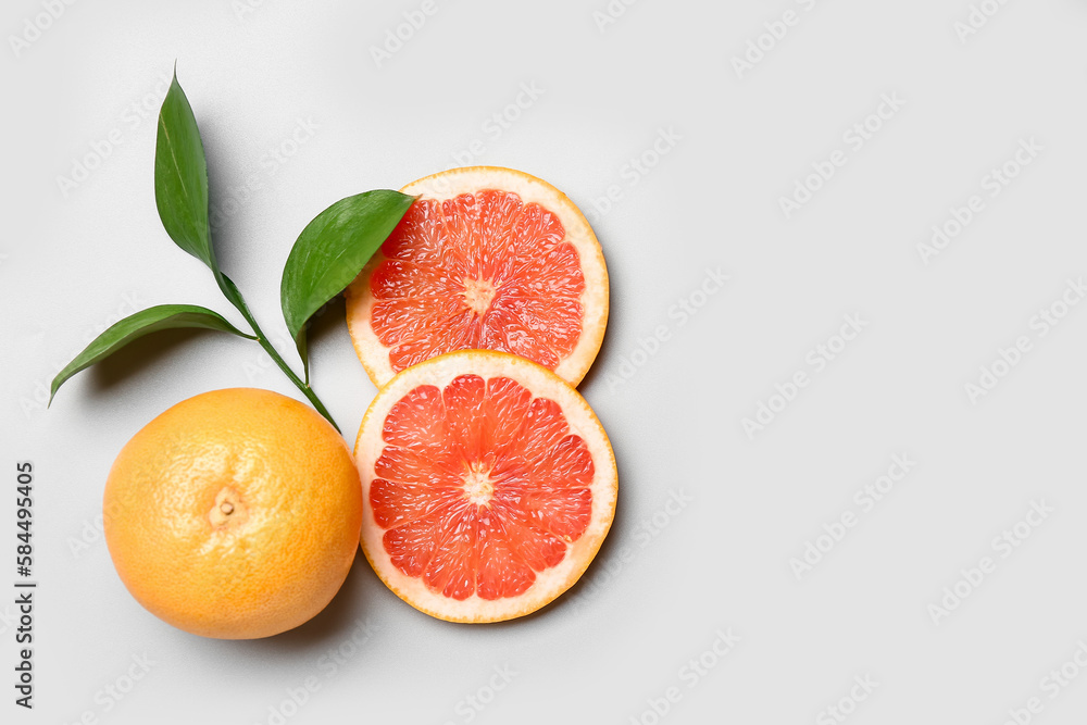 Ripe grapefruits and plant branch on light background