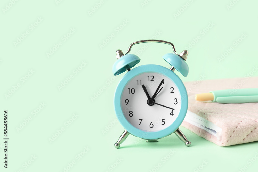 Alarm clock, pen and notebook on color background