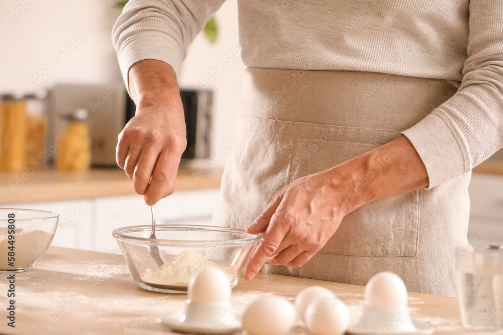 Male chef making dough for pasta at table in kitchen, closeup