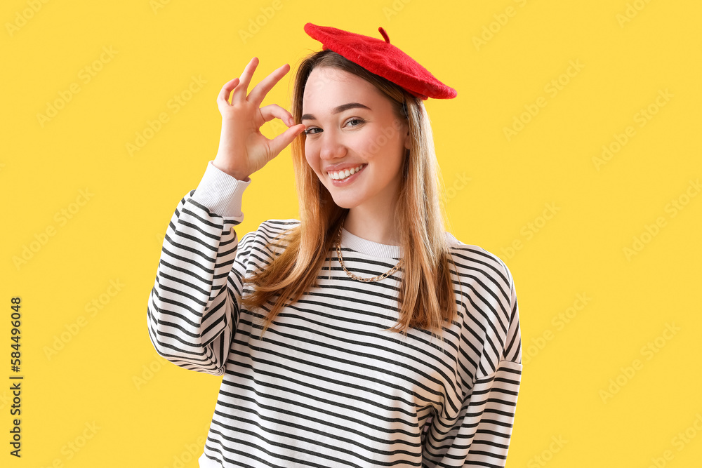 Young woman showing OK on yellow background