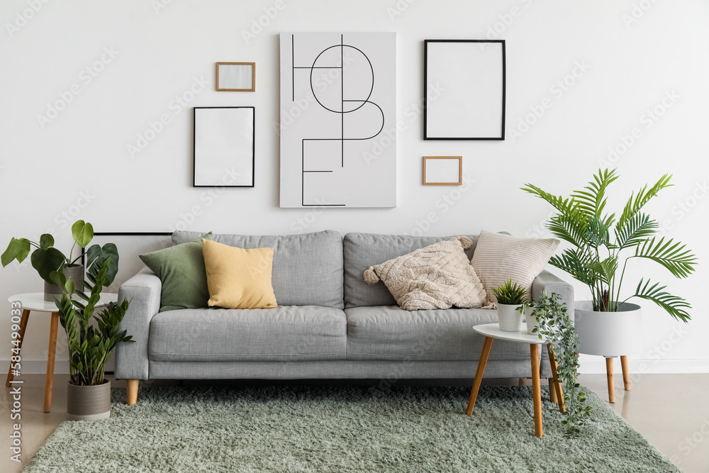 Interior of living room with cozy sofa, paintings and houseplants