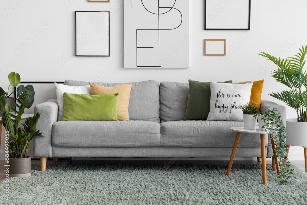 Interior of living room with cozy sofa, paintings and houseplants