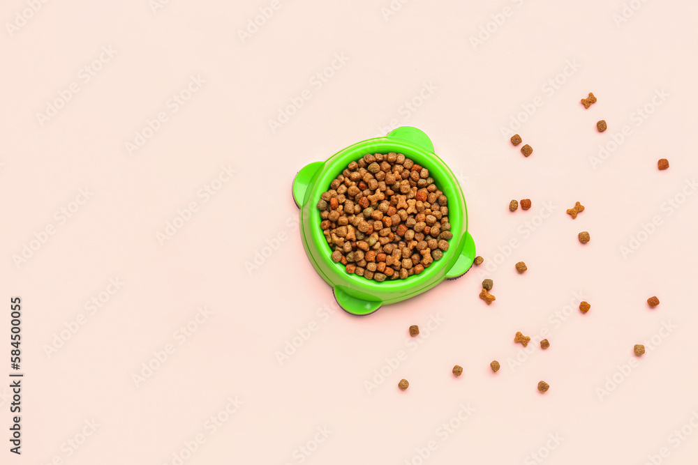 Bowl of dry pet food on pink background