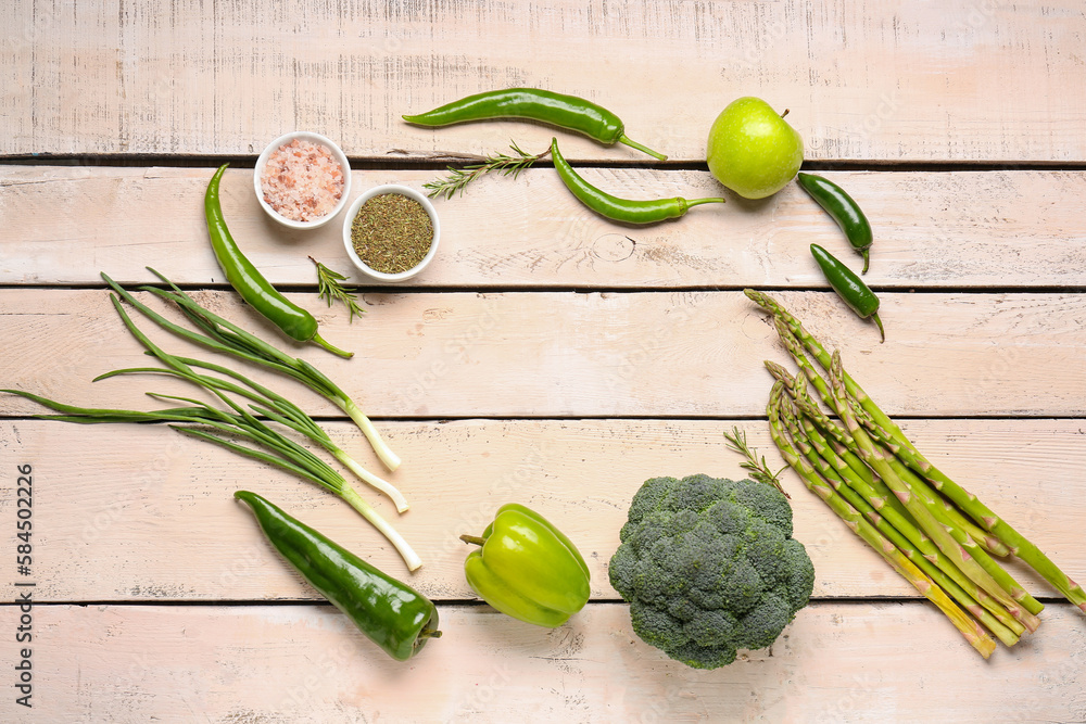 Frame made of different green vegetables on white wooden background