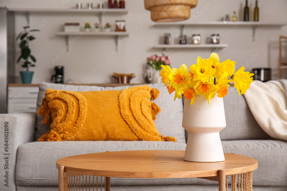 Vase with beautiful narcissus flowers on coffee table in modern living room