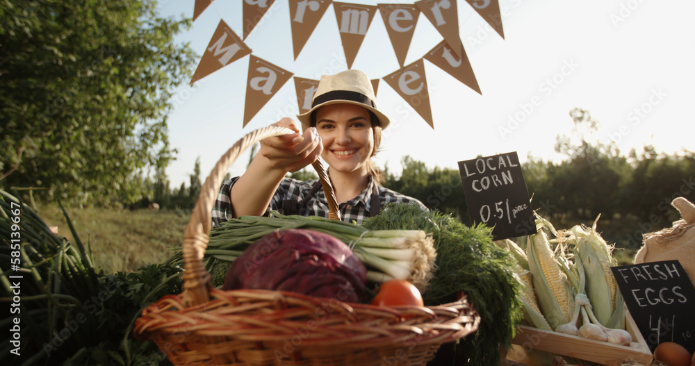 Young caucasian female farmer selling fresh local organic vegetables and fruits at stall of farmers 