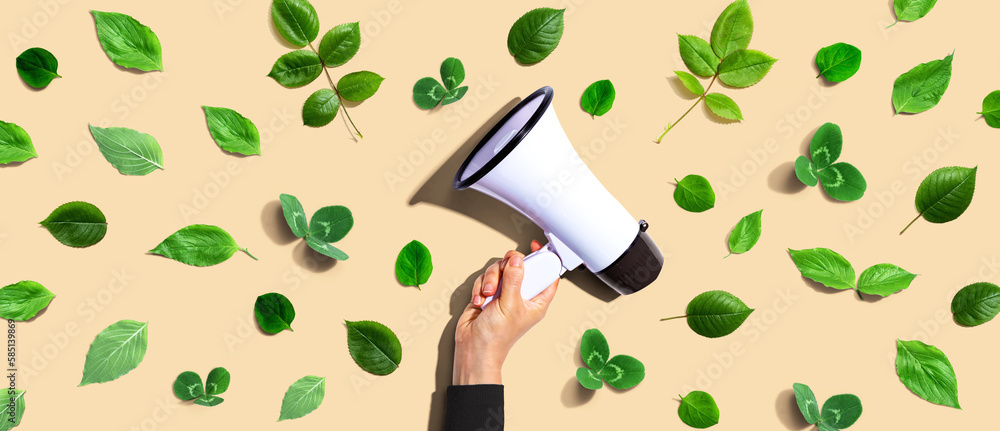 Person holding a megaphone with green leaves - flat lay