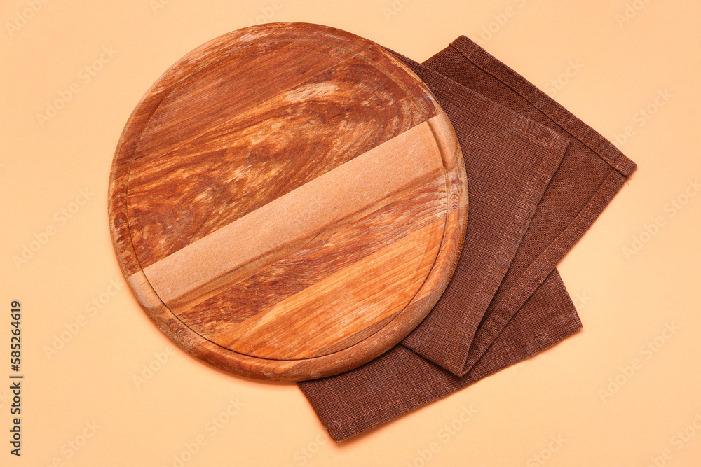 Wooden board and napkin on color background