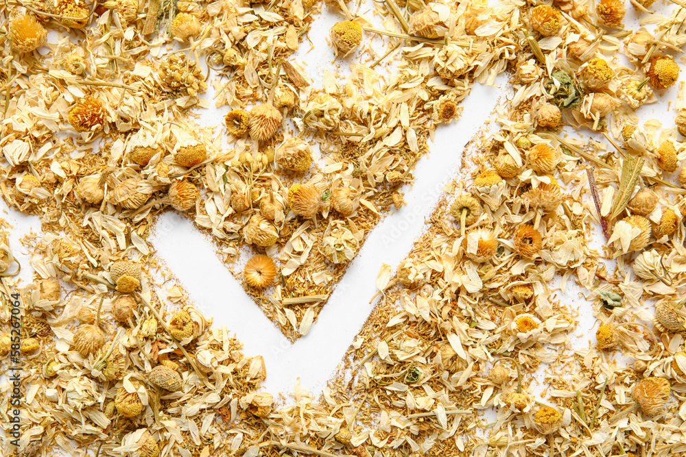 Check mark made of dried chamomile flowers on white background