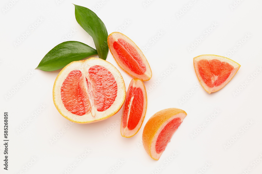 Pieces of ripe grapefruit and plant leaves on white background