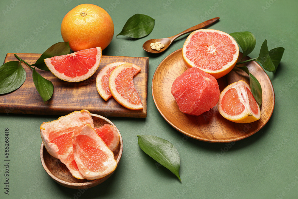 Composition with ripe grapefruits and plant leaves on green background