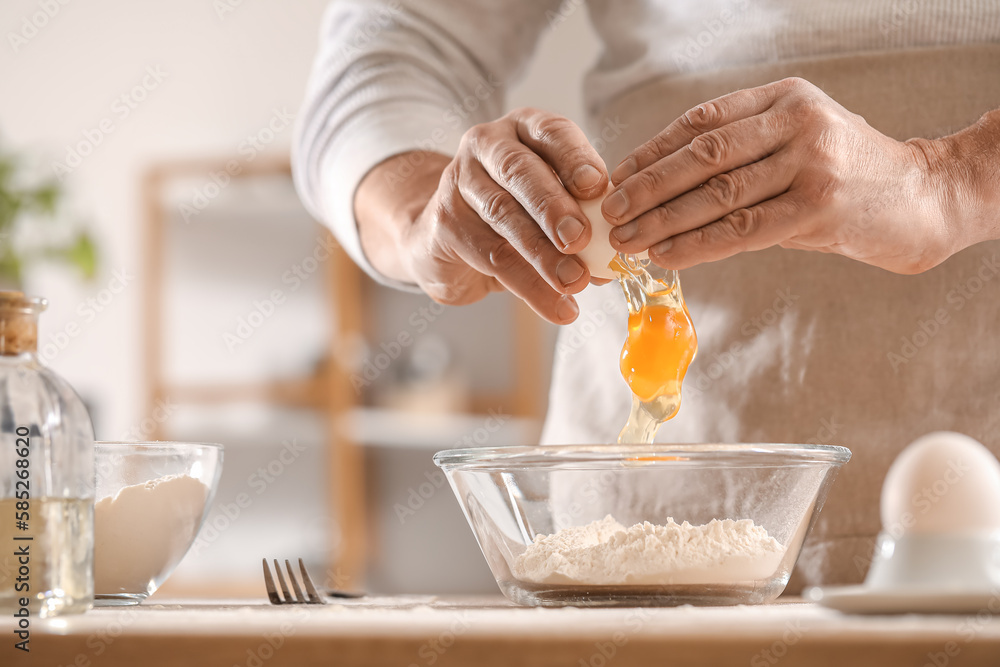 Male chef making dough for pasta at table in kitchen, closeup