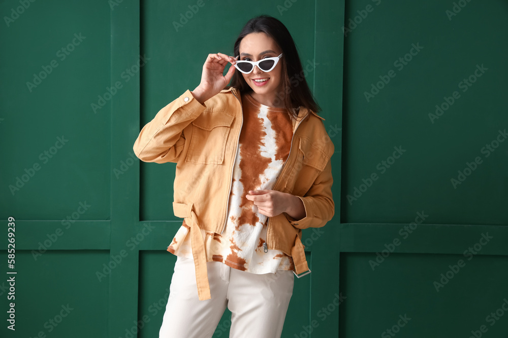 Stylish young woman in tie-dye t-shirt on green background