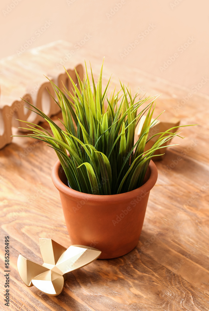 Artificial grass with decor on table near beige wall