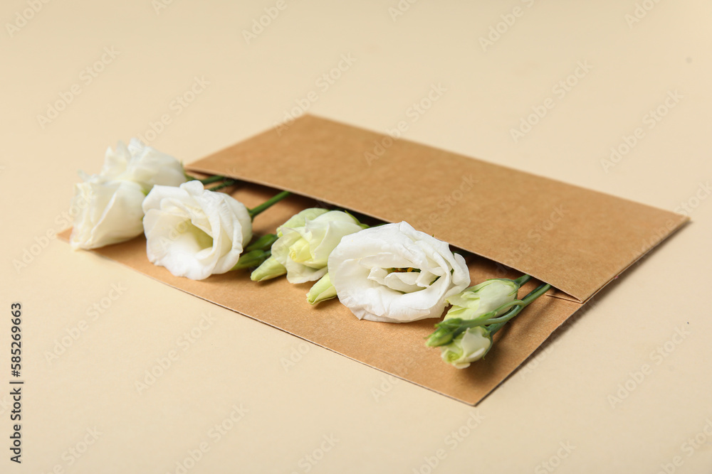 Craft envelope with beautiful eustoma flowers on color background