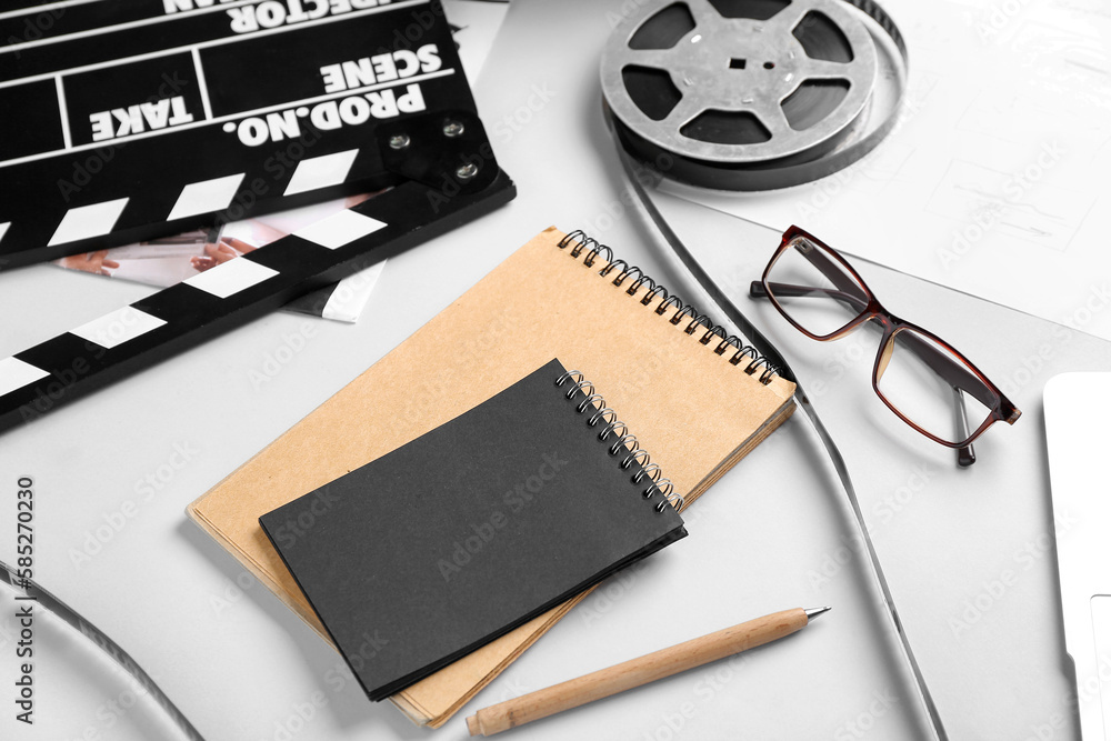 Notebooks with film reel and movie clapper on grey background, closeup