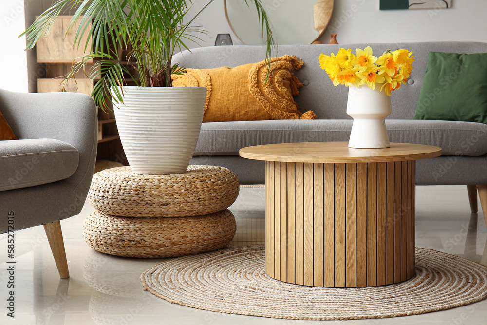 Vase with narcissus flowers on coffee table in cozy living room