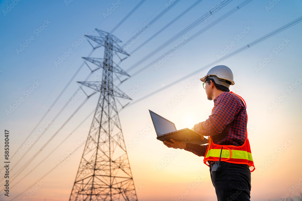 Asian electrical engineers checking location using a notebook computer standing at a power station t