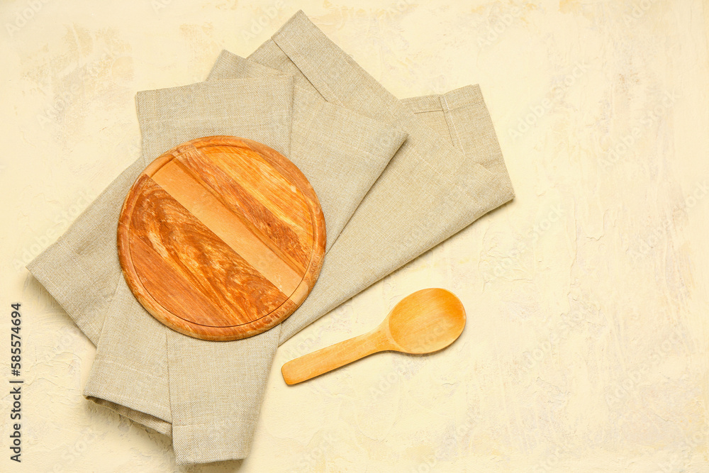 Wooden board, spoon and napkin on light background