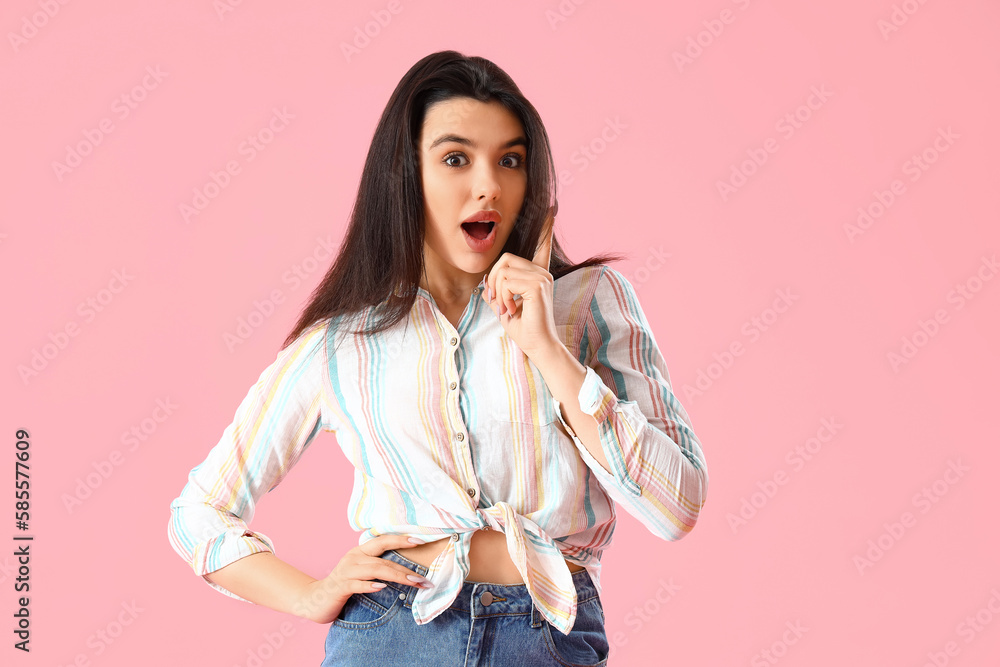 Surprised young woman in shirt on pink background