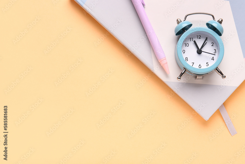 Notebook, pen and alarm clock on color background