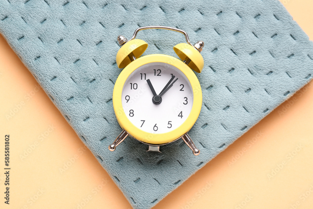 Notebook and alarm clock on color background, closeup