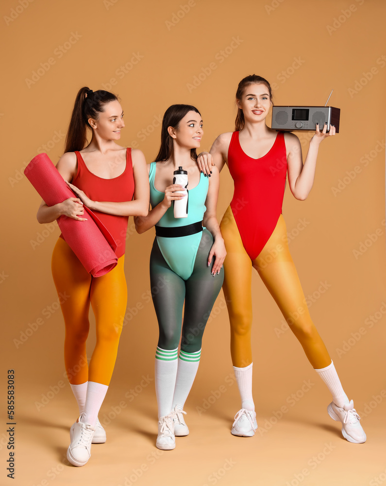 Sporty young women going to do aerobics on beige background