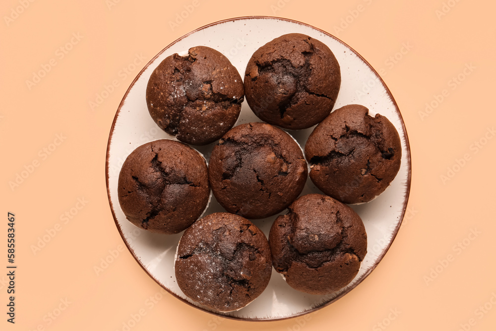 Plate with tasty chocolate cupcakes on beige background